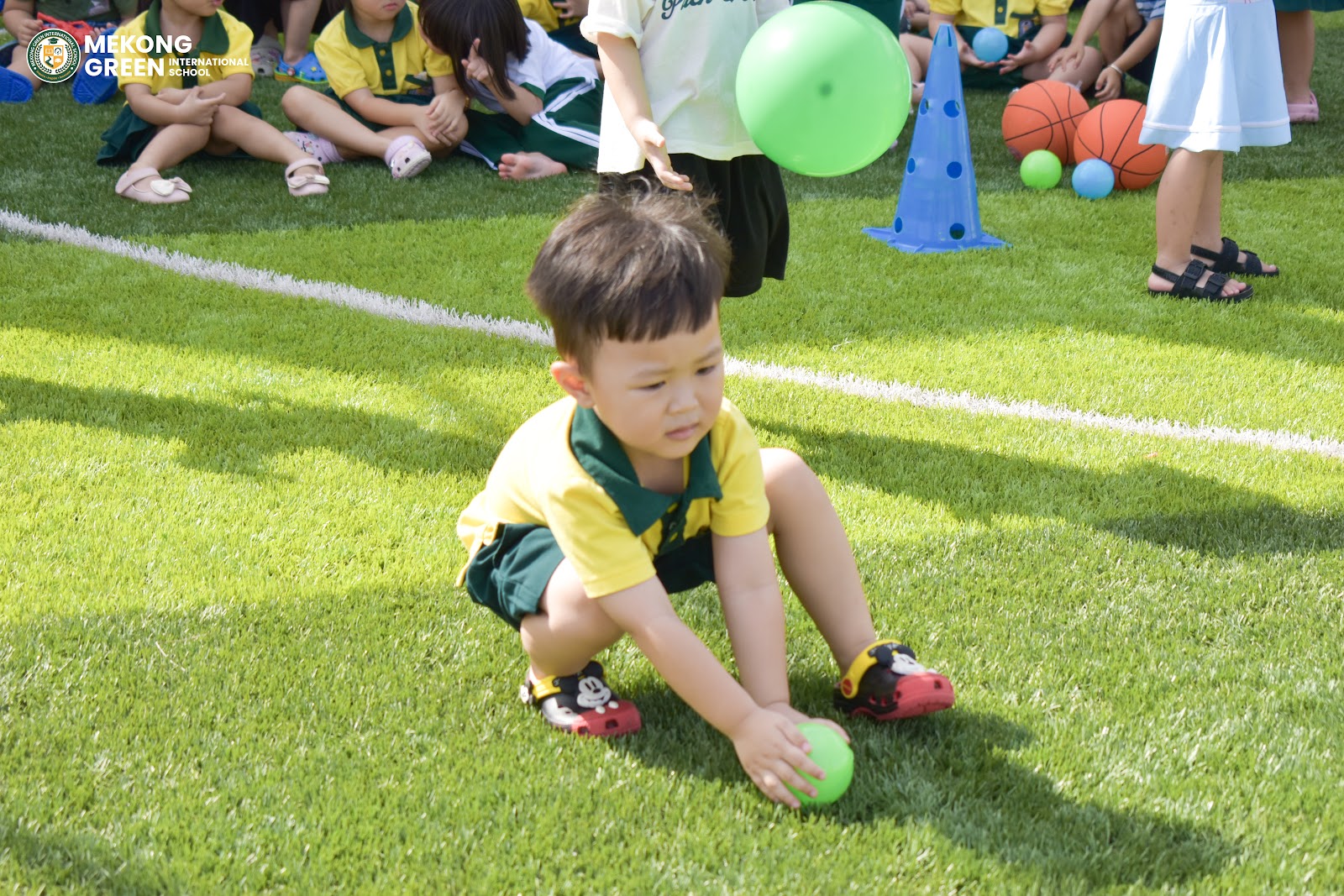 Bé tập trung thực hiện thử thách vận động trên sân cỏ